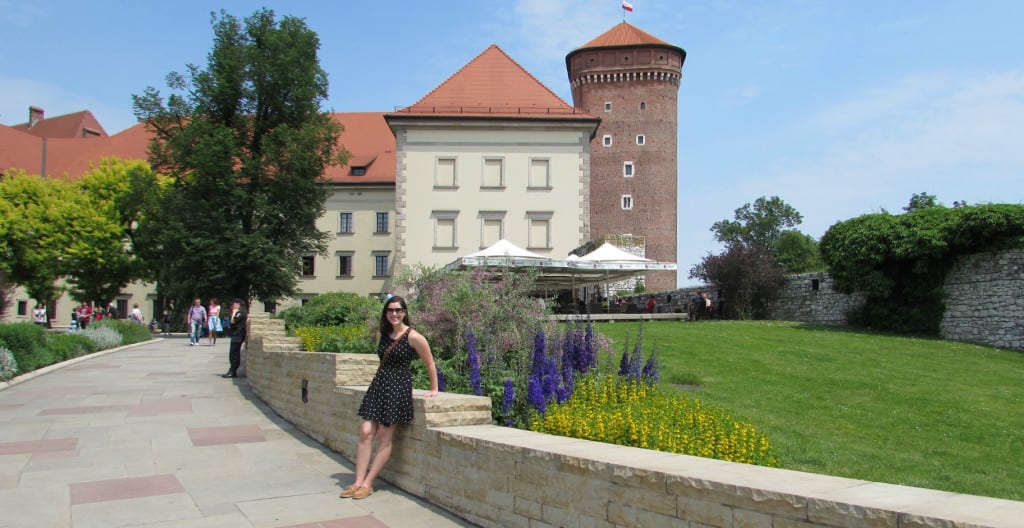 穿着黑色连衣裙的凯特·斯道姆站在瓦维尔城堡的院子里——在克拉科夫的2天行程中，一定要在这里停留!