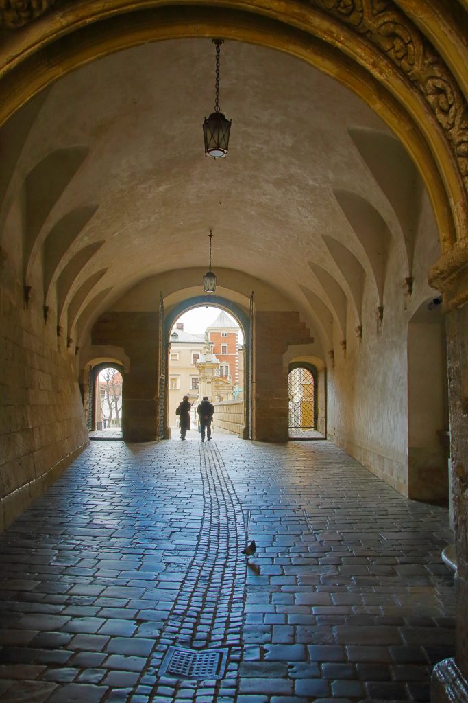 在波兰瓦维尔城堡的一个拱门覆盖的鹅卵石路径的照片