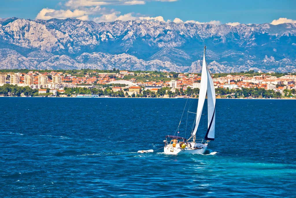 水面上的帆船，背景是克罗地亚扎达尔市，后面是山脉