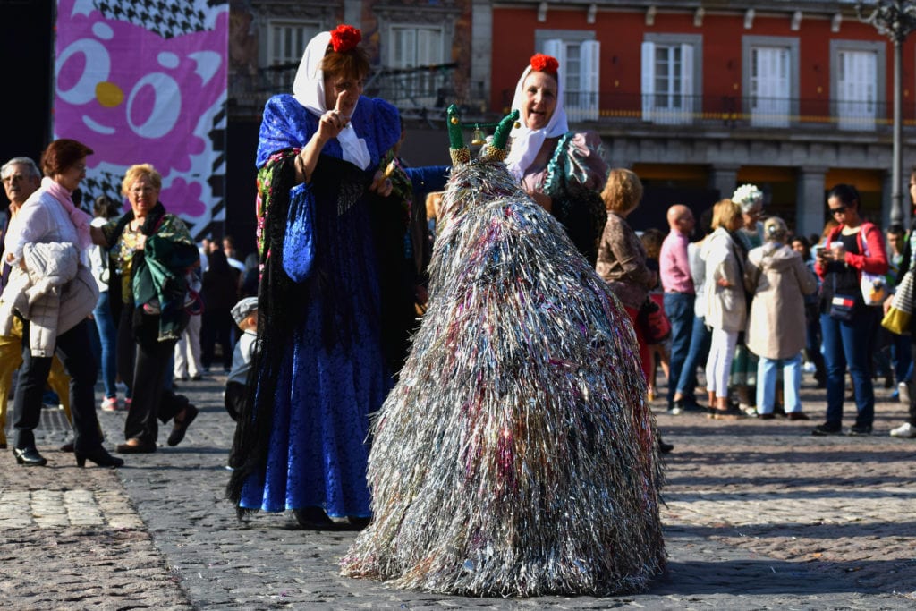 两名身穿传统服饰的妇女，前景是用流苏做成的狗装