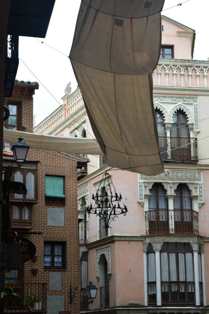 西班牙托莱多的街道照片，右边有一座粉红色的建筑