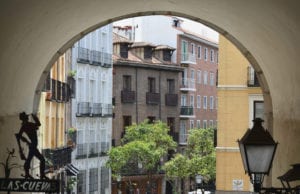 西班牙马德里的拱门照片，背景中可见五颜六色的建筑。像这样的风景是在预算内享受马德里的一种免费方式