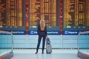 一名金发女子站在机场的登机牌前，包里装着所有的旅行必需品必威体育官方登录