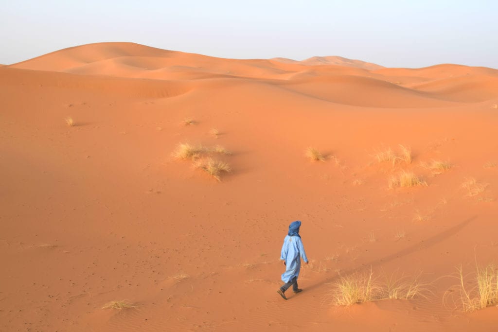 在摩洛哥沙漠之旅中，穿着蓝色衣服的小男孩正在穿越沙丘