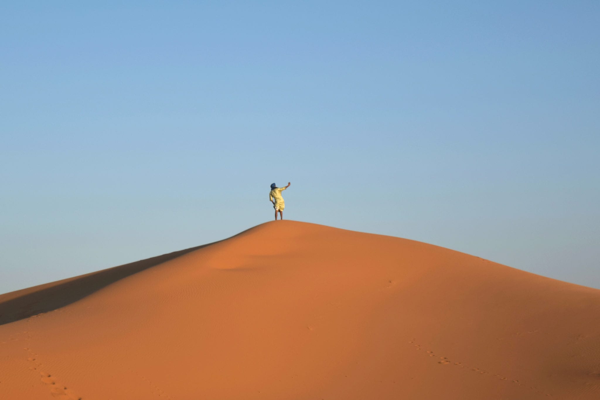 在摩洛哥撒哈拉沙漠之旅中，一名男子在沙丘上自拍