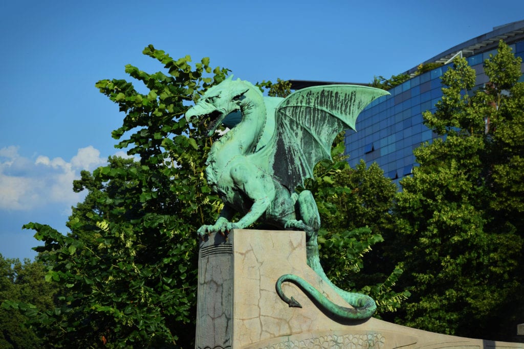 Green dragon statue perched on Dragon Bridge in Ljubljana Slovenia, one of the most fun cities in Europe to visit