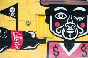 一名男子在黄色背景上拿着可口可乐的壁画，是墨西哥旅游预算中最好的东西之一必威体育官方登录