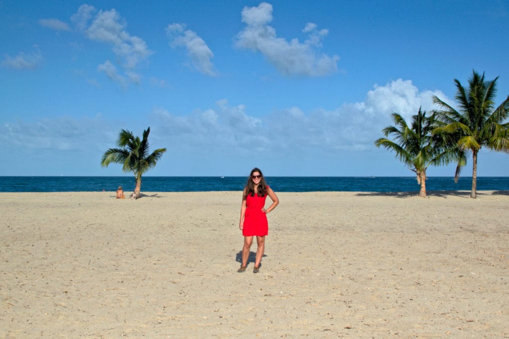 身着红裙的凯特站在伯利兹placencia海滩上
