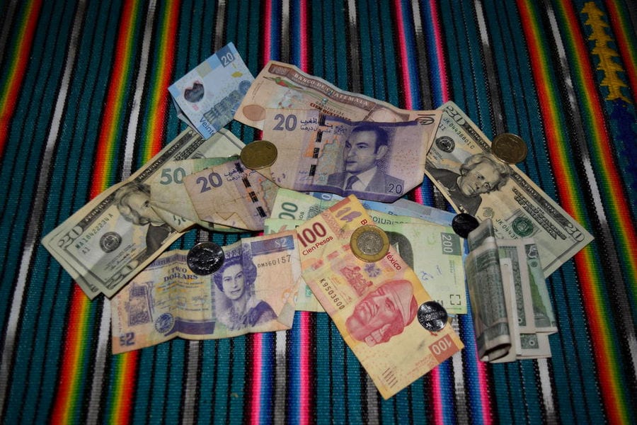 一堆不同货币的钱坐在条纹桌布上