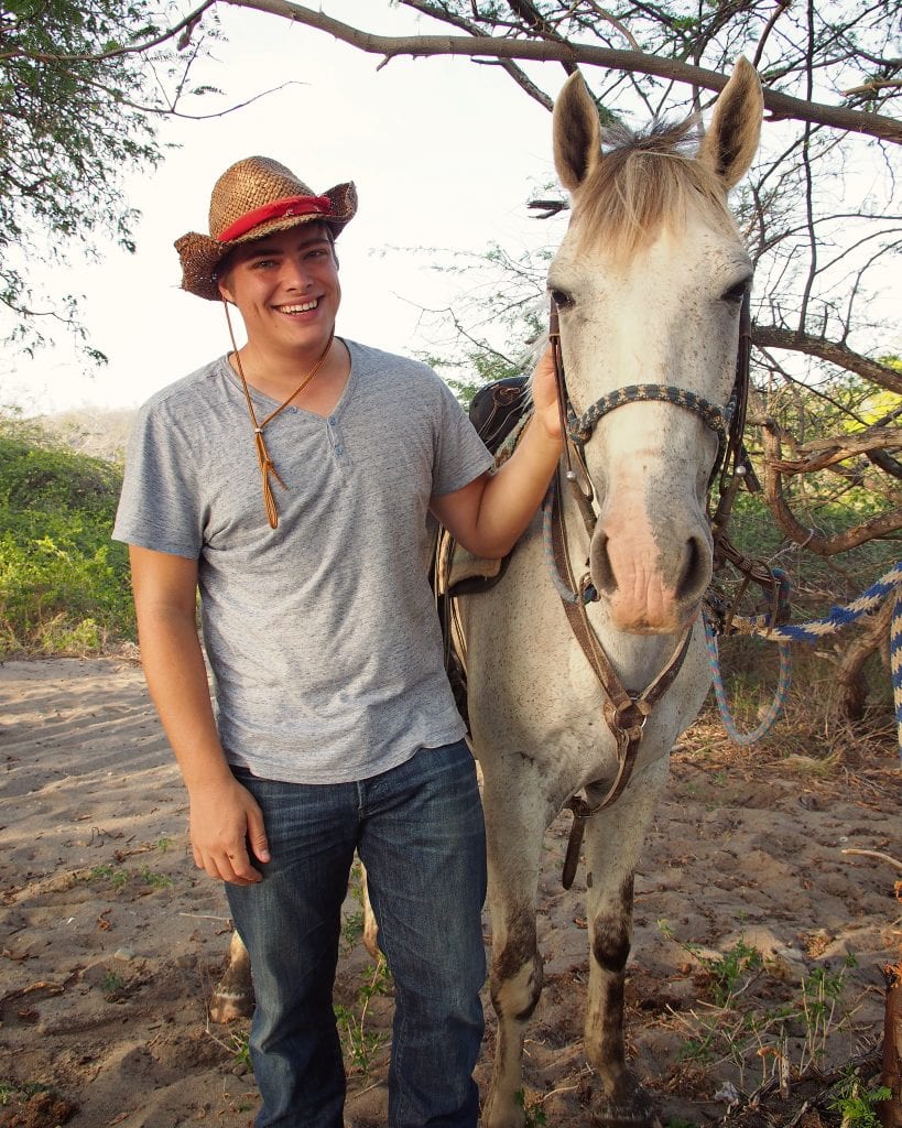 杰里米·斯托姆戴着牛仔帽，和一匹白色的尼加拉瓜圣胡安站在一起