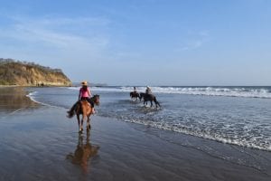 凯特穿着粉色衬衫在尼加拉瓜的海滩上骑马