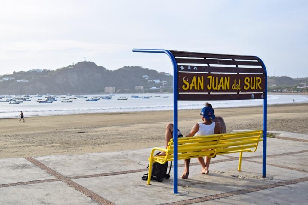 一对夫妇坐在尼加拉瓜南部圣胡安长凳前的黄蓝相间的长凳上