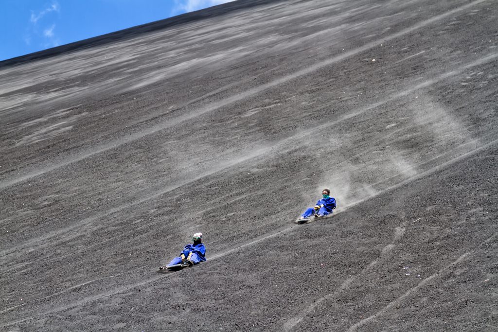 两个穿着蓝色连体裤的火山游客在塞罗内格罗火山上