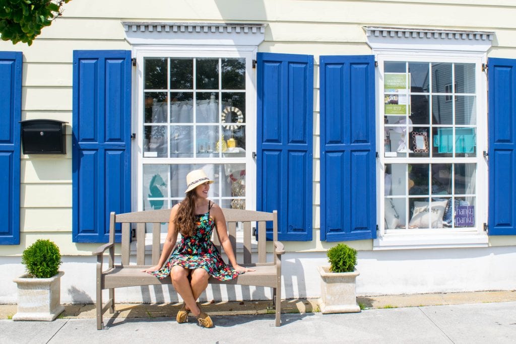在北卡罗来纳州博福特好玩的事情:一个女孩坐在带有蓝色百叶窗的精品店前的长椅上