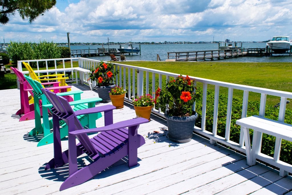 4把彩色沙滩椅放在白色甲板上，俯瞰北卡罗来纳州大西洋海滩的博格湾