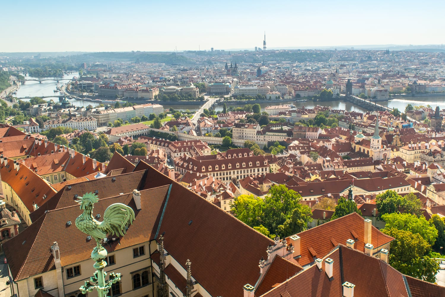 从圣维塔斯大教堂顶部俯瞰布拉格的天际线，左边前景中有一只绿色的小公鸡
