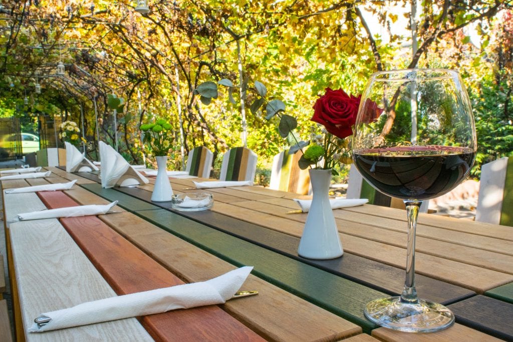 一杯红酒坐在户外餐桌上，就像参观布加勒斯特景点时看到的那样