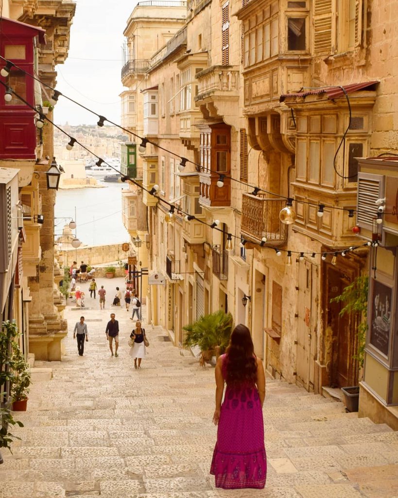 凯特在马耳他瓦莱塔的一条小街上身穿粉色连衣裙