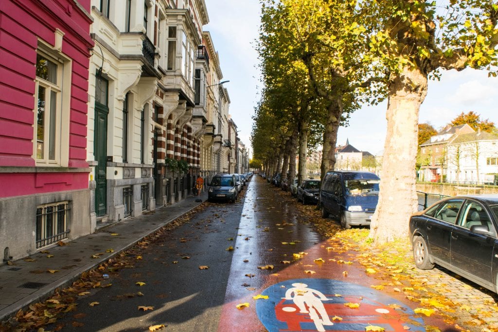 比利时根特空荡荡的街道，远处可以看到几辆汽车，地上有黄色的树叶——制定秋季去欧洲的打包清单时，要记住这个潮湿的天气!