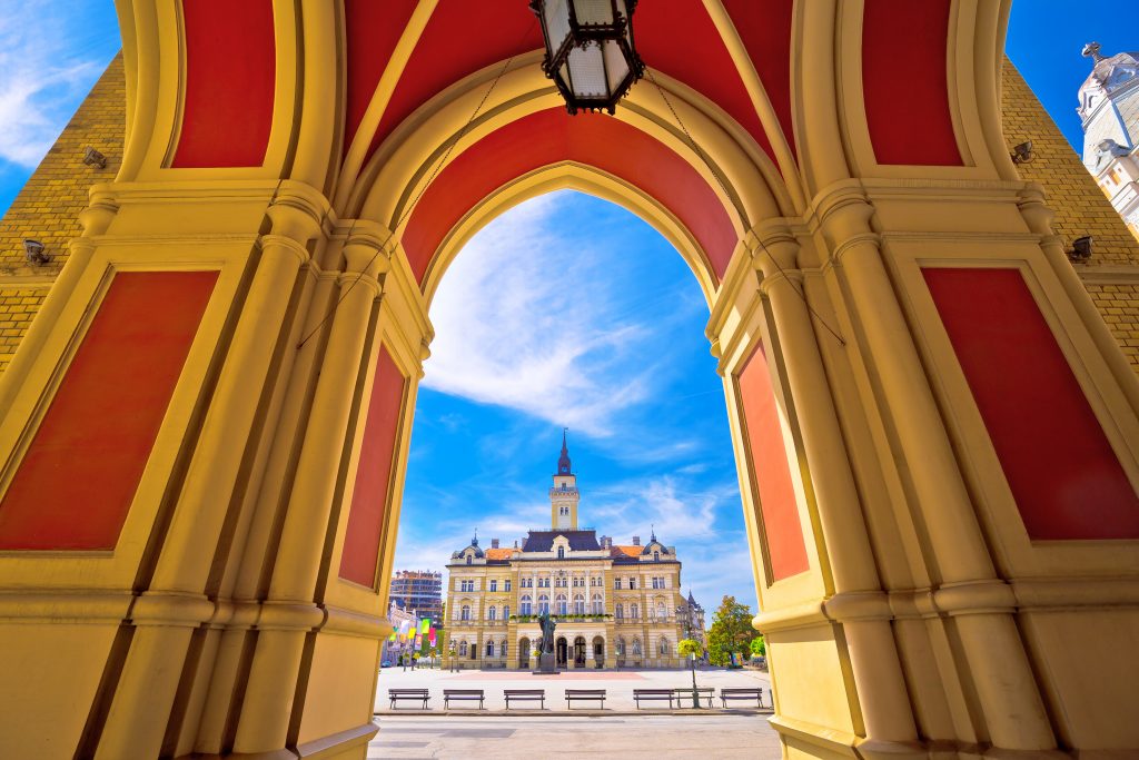 透过色彩斑斓的红色和黄色拱门看到的塞尔维亚自由广场诺维萨德是欧洲最便宜的旅游城市之一