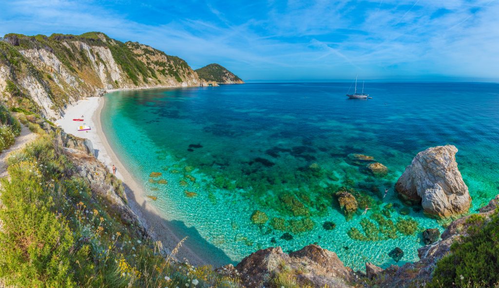 明亮的蓝绿色海滩，左面可见厄尔巴岛的陆地，这是意大利托斯卡纳地区最好的旅游胜地之一