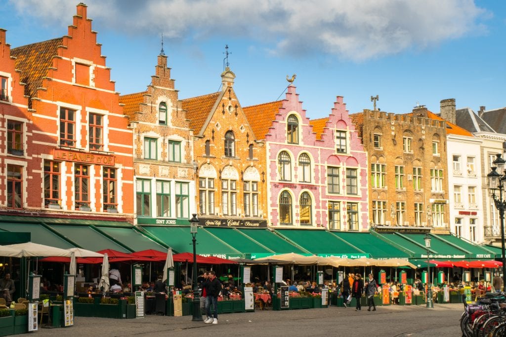 Bruges Main Square with green awnings in front of the buildings--this storybook village is a fun place to add to your 2 weeks in Europe itinerary!