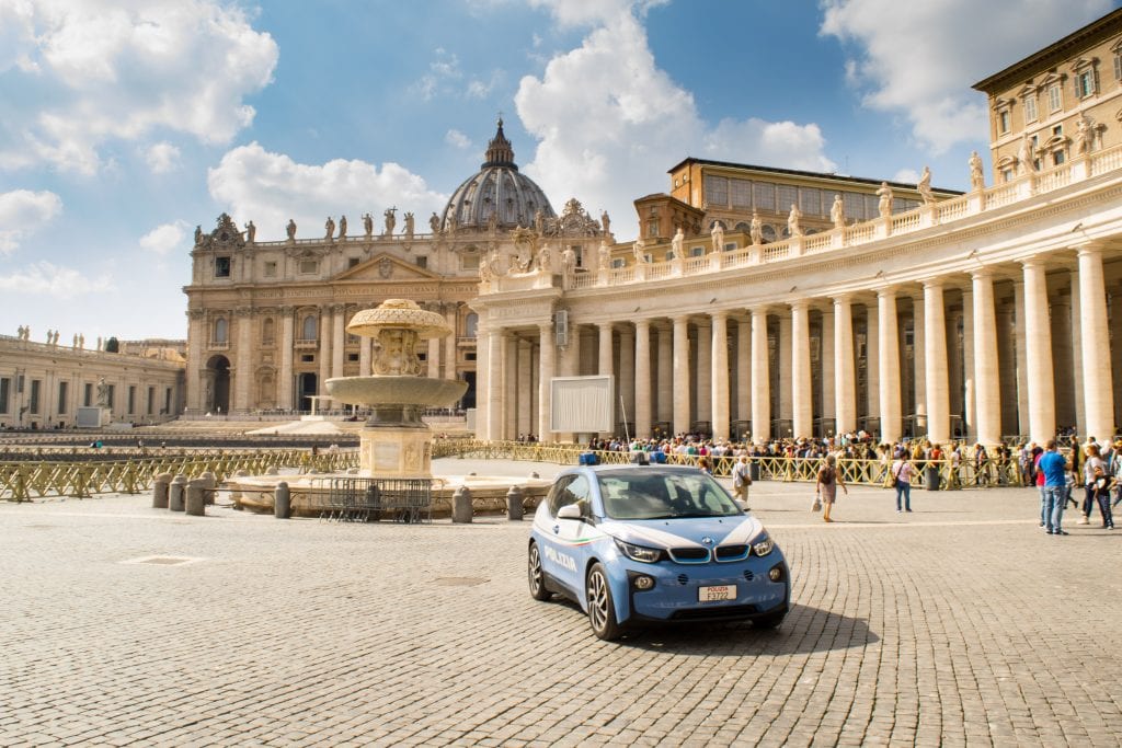 阳光明媚的日子里，圣彼得广场上停着汽车——游览梵蒂冈城时，参观这个广场是必看的!