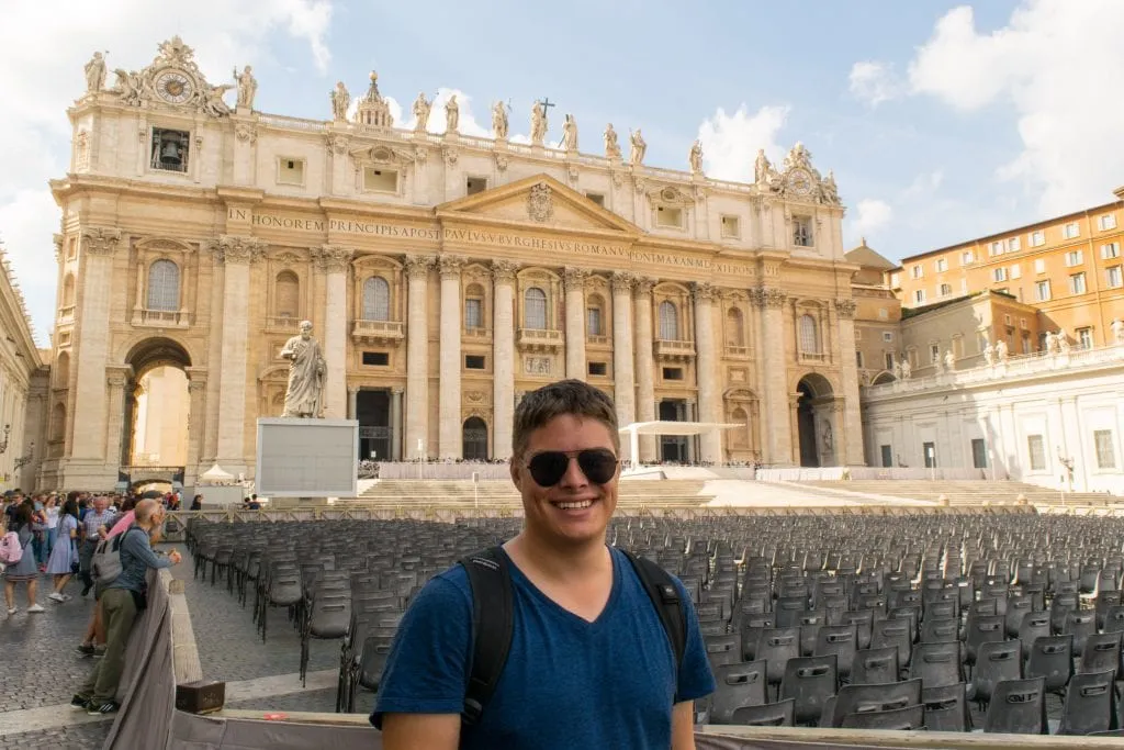 杰里米·斯道姆戴着飞行员太阳镜，在参观梵蒂冈城罗马时站在圣彼得大教堂前