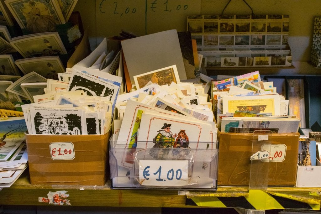 一堆明信片出售在Libreria Acqua Alta威尼斯。箱子上标有1欧元的价格标签。