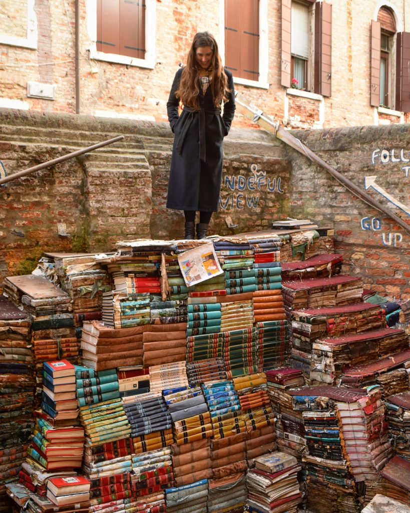 在意大利威尼斯图书馆，凯特站在摆满书的楼梯上
