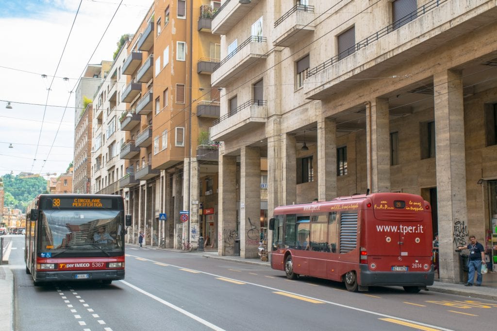红色公共汽车行驶在博洛尼亚的一条街道上