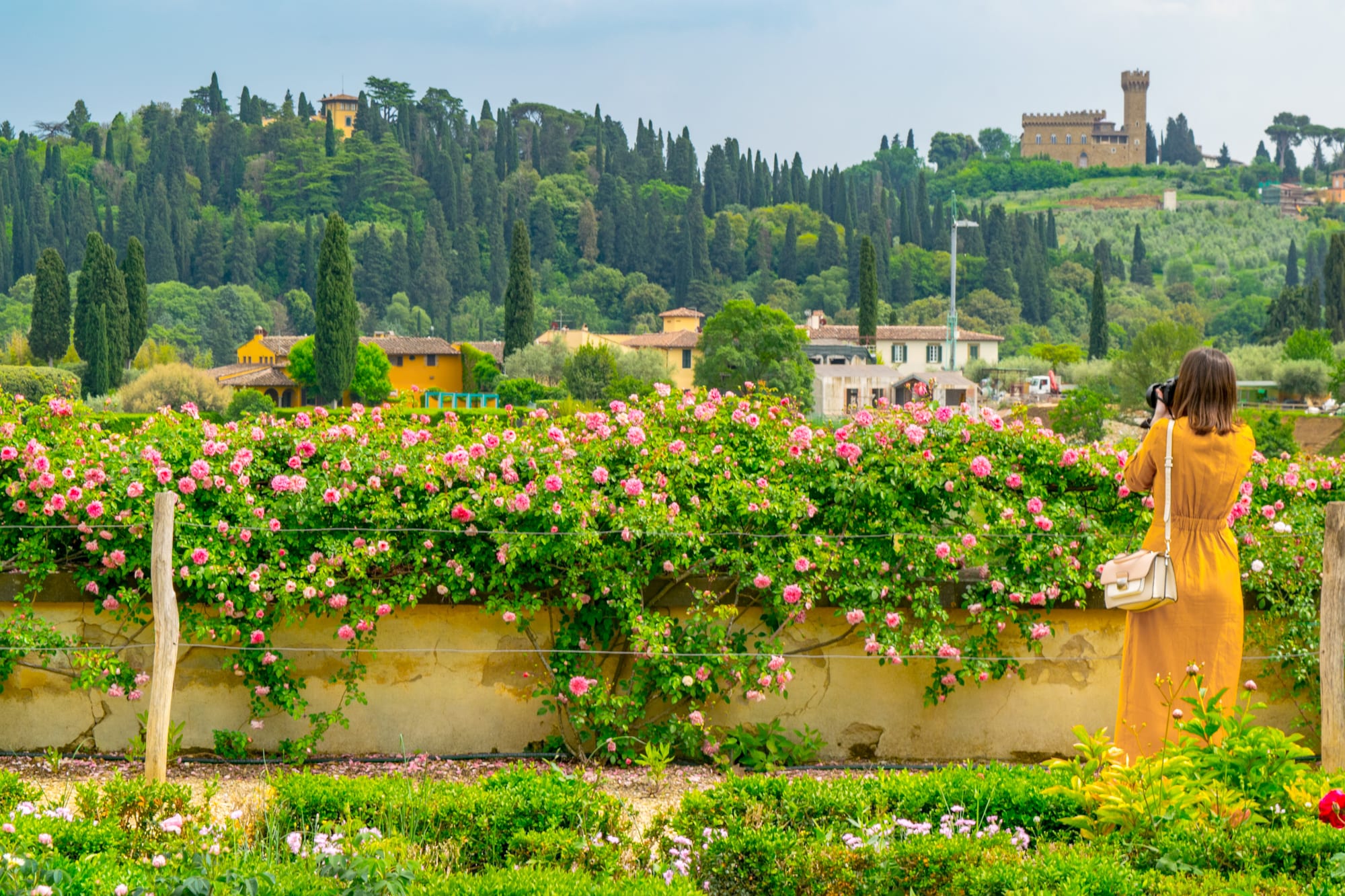 一名身穿黄色连衣裙的女子在波波利花园拍照，这是意大利佛罗伦萨最上传到instagram的景点之一