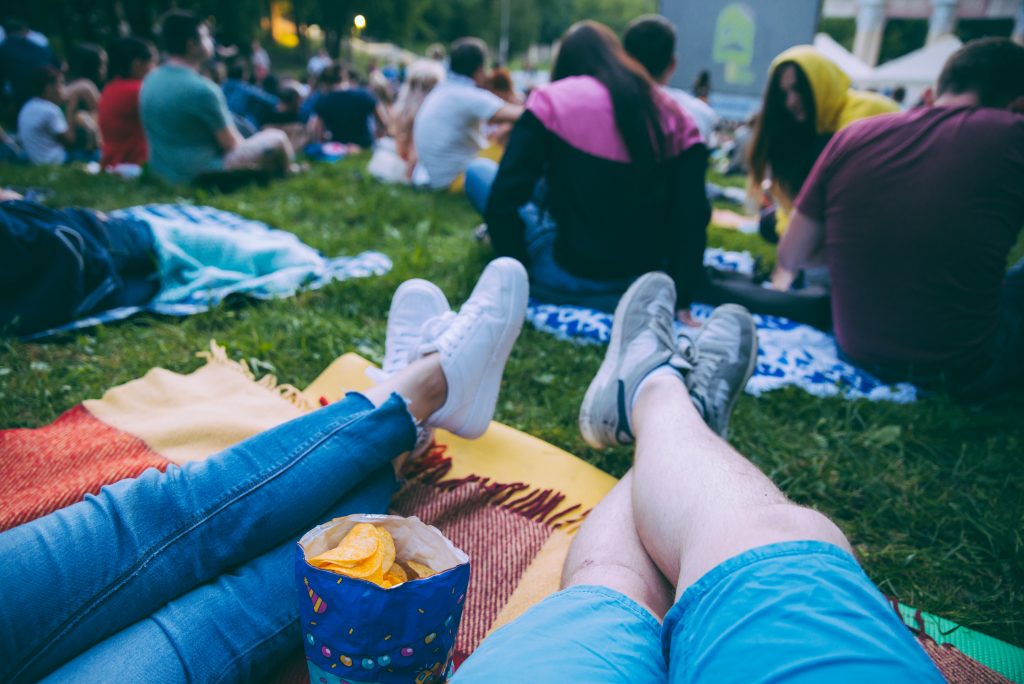 人们披着野餐毯准备在公园里看电影