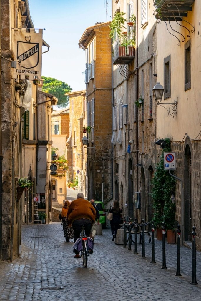 在意大利奥维多，一名男子骑着自行车走在鹅卵石街道上