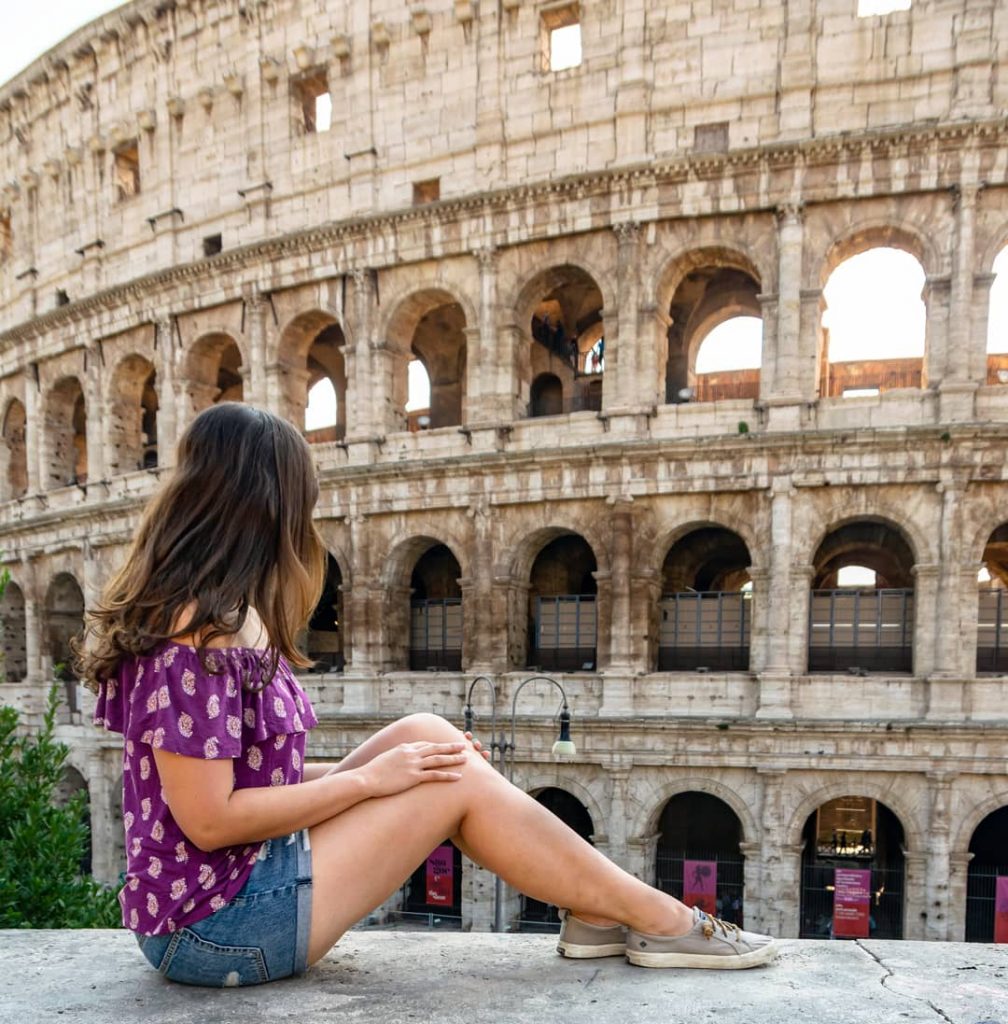凯特王妃身穿紫色衬衫坐在罗马斗兽场前，斗兽场是意大利罗马行程的主要景点之一