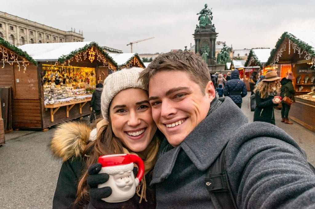 凯特和杰里米在维也纳圣诞市场自拍。凯特举着一个红白相间的圣诞老人马克杯。