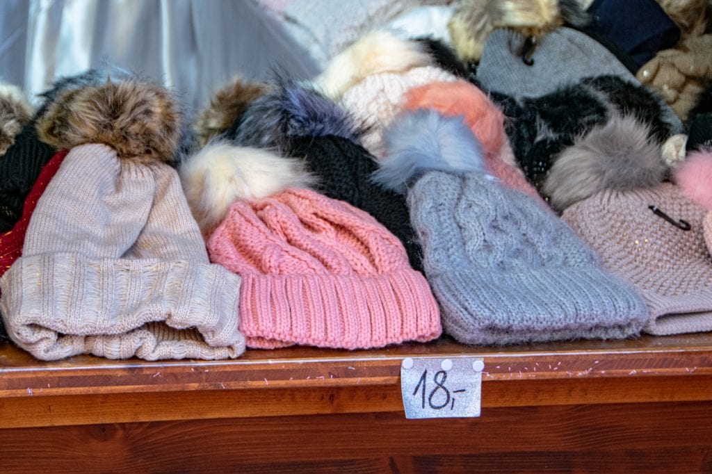 奥地利因斯布鲁克圣诞市场的木桌上放着一堆针织帽——你可以买到很多这样的纪念品，所以不要在你的欧洲冬天的打包清单上放太多的配件!