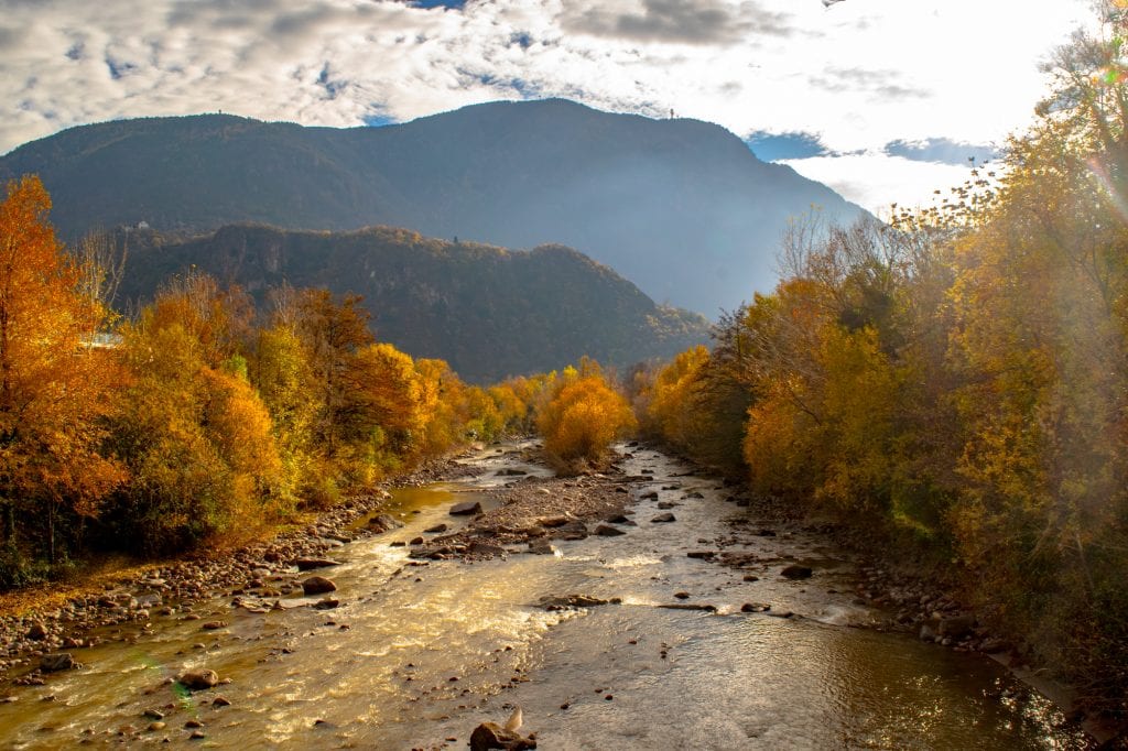 如何使用欧洲铁路通票:波尔扎诺的河流被秋叶环绕的照片。