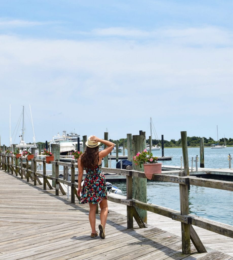 凯特·斯道姆穿着花裙子走在木板路上，这是北卡罗来纳州博福特最好的事情之一，背景是帆船
