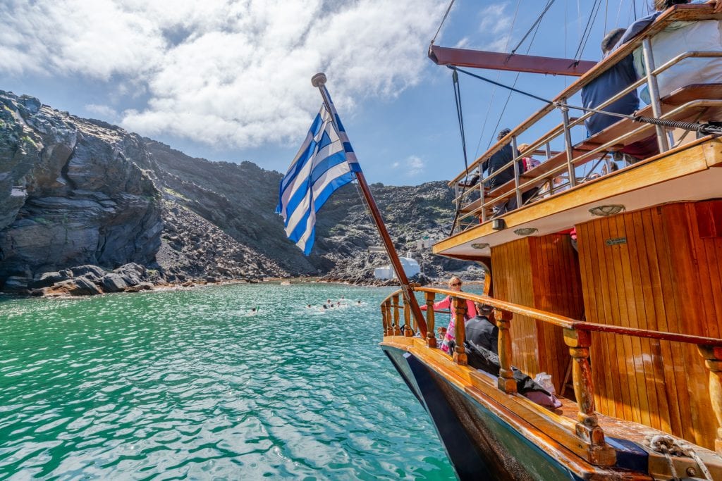 悬挂希腊国旗的游船在火山温泉，圣托里尼3天行程