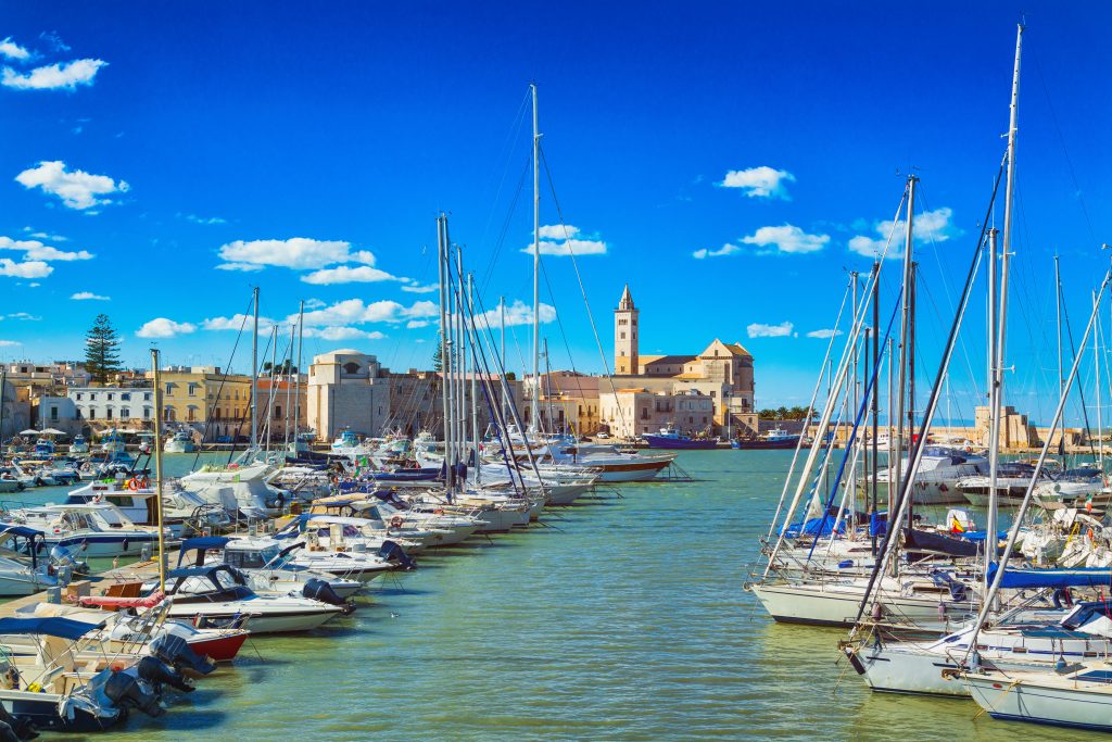 火车普利亚港，前景是帆船，意大利最好的沿海城镇之一