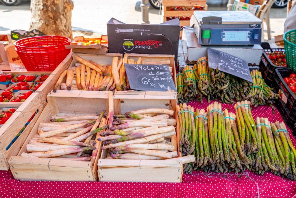 在普罗旺斯艾克斯的户外食品市场，收银台前摆放着一盒盒白色和绿色的芦笋