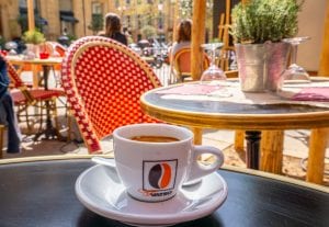 在法国，一顿典型的法式早餐期间，我们坐在户外的黑色桌子上喝咖啡，背景是一把红色的椅子