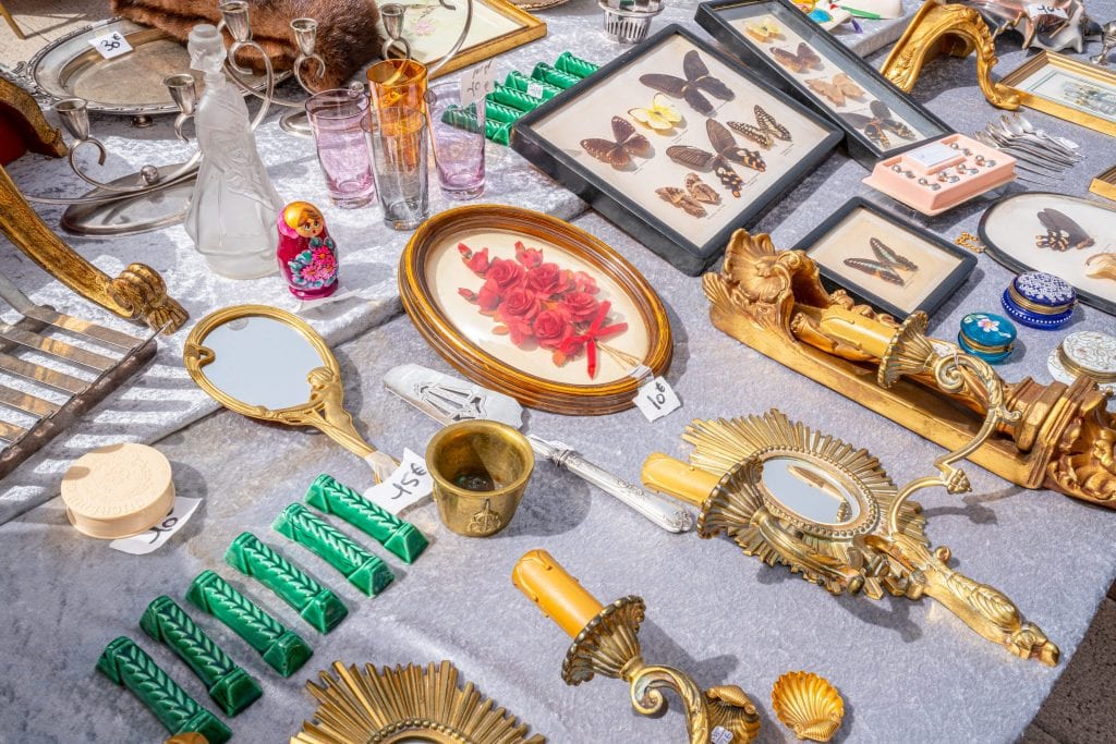 Collection of antique items for sale, laid out on a table at a market in Nice, as seen during a south of France vacation.