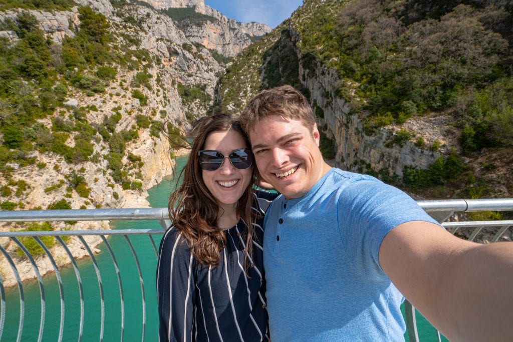 Selfie of Kate and Jeremy in front of the Verdon Gorge. Both are wearing blue shirts and Kate is wearing sunglasses.