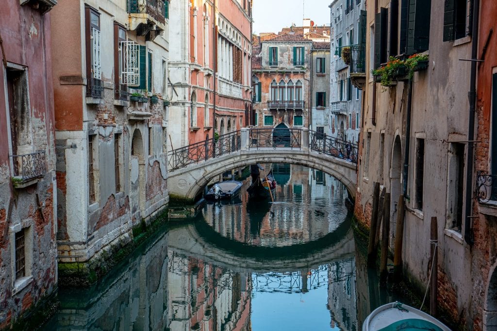 人行桥倒映在威尼斯一条安静的运河上。威尼斯是一个迷人的城市，也是意大利一些非常有趣的事实的发源地