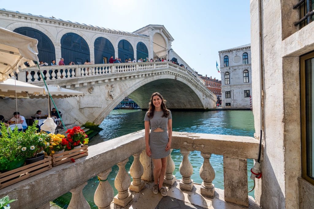 Girl in striped dress standing in front of Rialto Bridge in Venice Italy