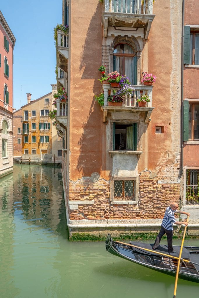 威尼斯运河的照片，船夫在角落里划桨