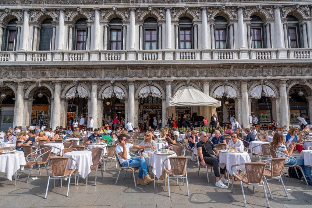 游客在著名的威尼斯广场圣马克的户外咖啡馆里喝咖啡，在意大利要付哥德托