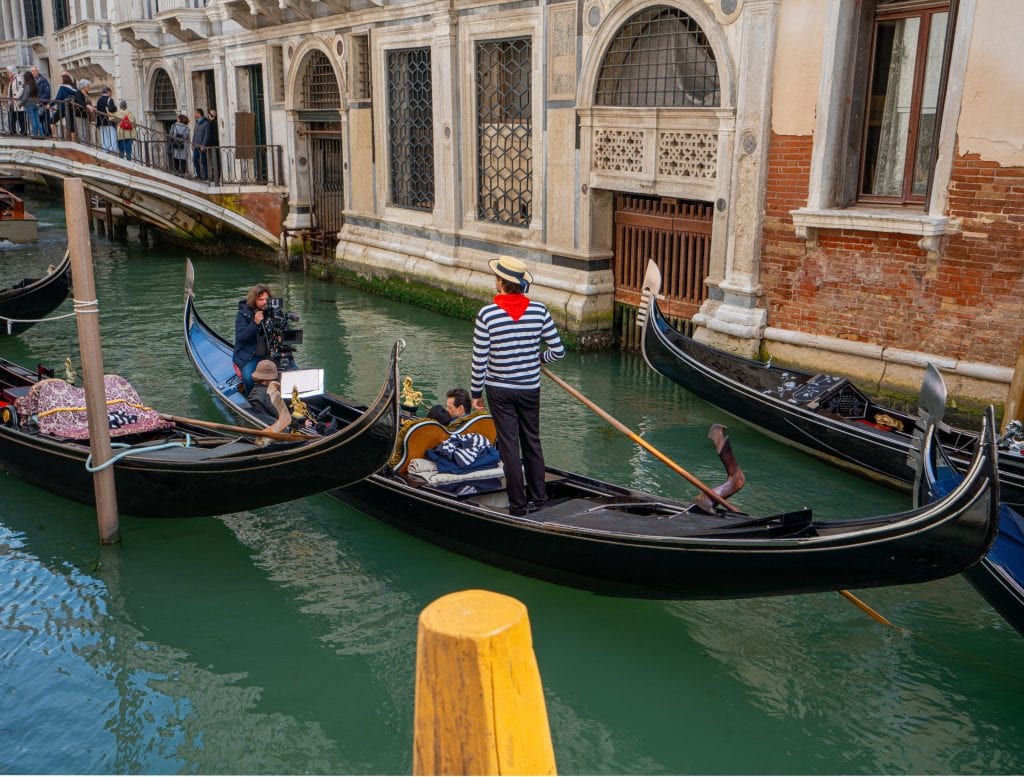 威尼斯的贡多拉之旅，一个贡多拉人站在画面中央。船夫戴着红色的大手帕。